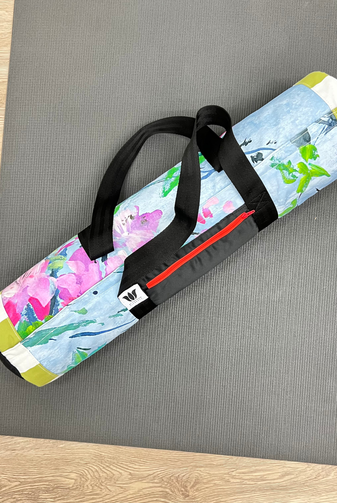 Colorful floral-patterned yoga mat bag with a black straps on yoga mat