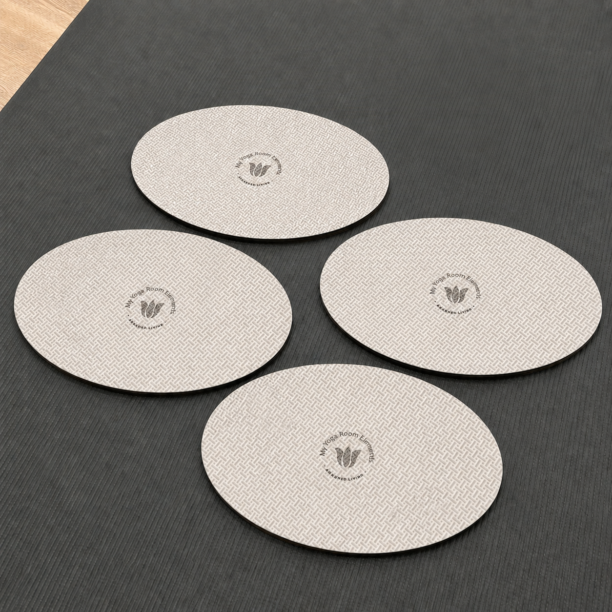 Four round beige yoga pads with a logo on a dark surface