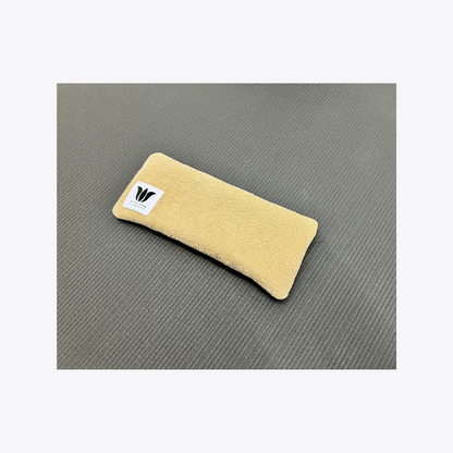 Beige eye pillow with a logo on a gray surface