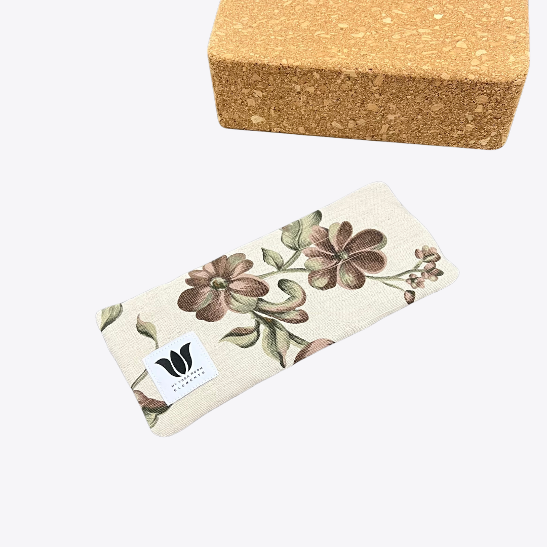 Floral-patterned yoga eye pillow with cork block on a white background