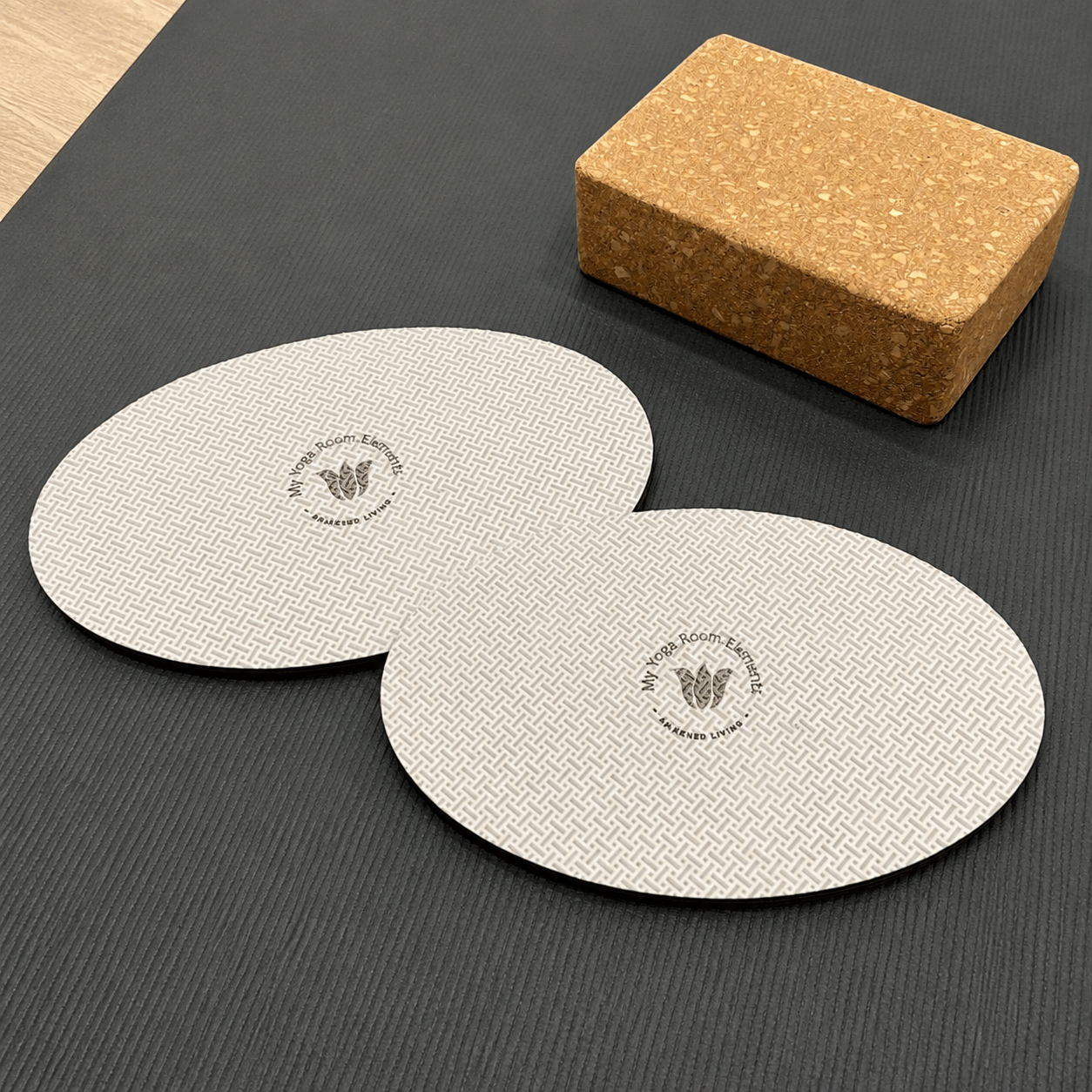 Two yoga pads and a cork block on a dark surface