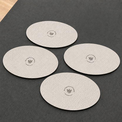 Four round beige yoga pads with a logo on a dark surface