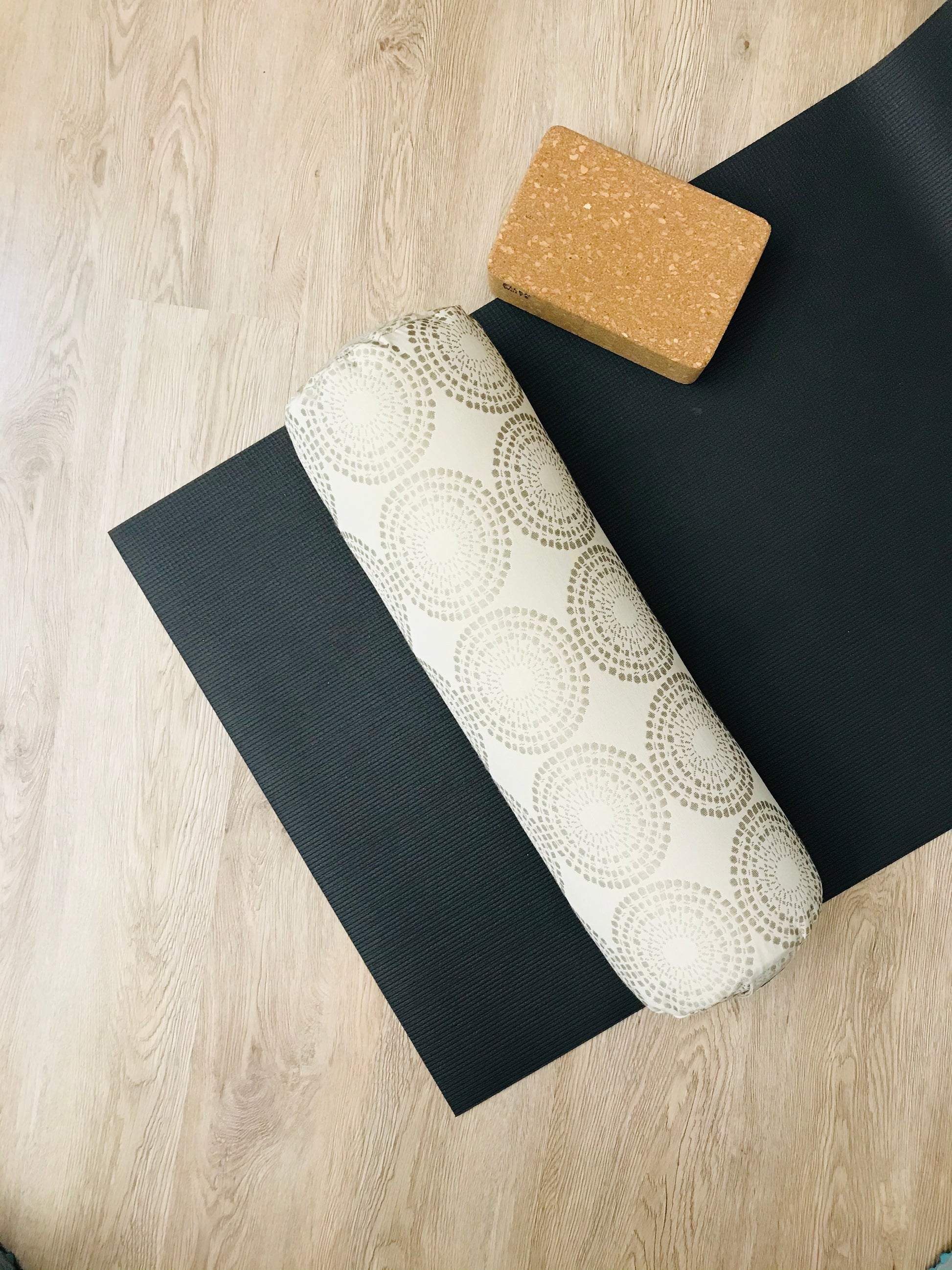 Round yoga bolster displayed on yoga mat, showing size of yoga mat to consumer