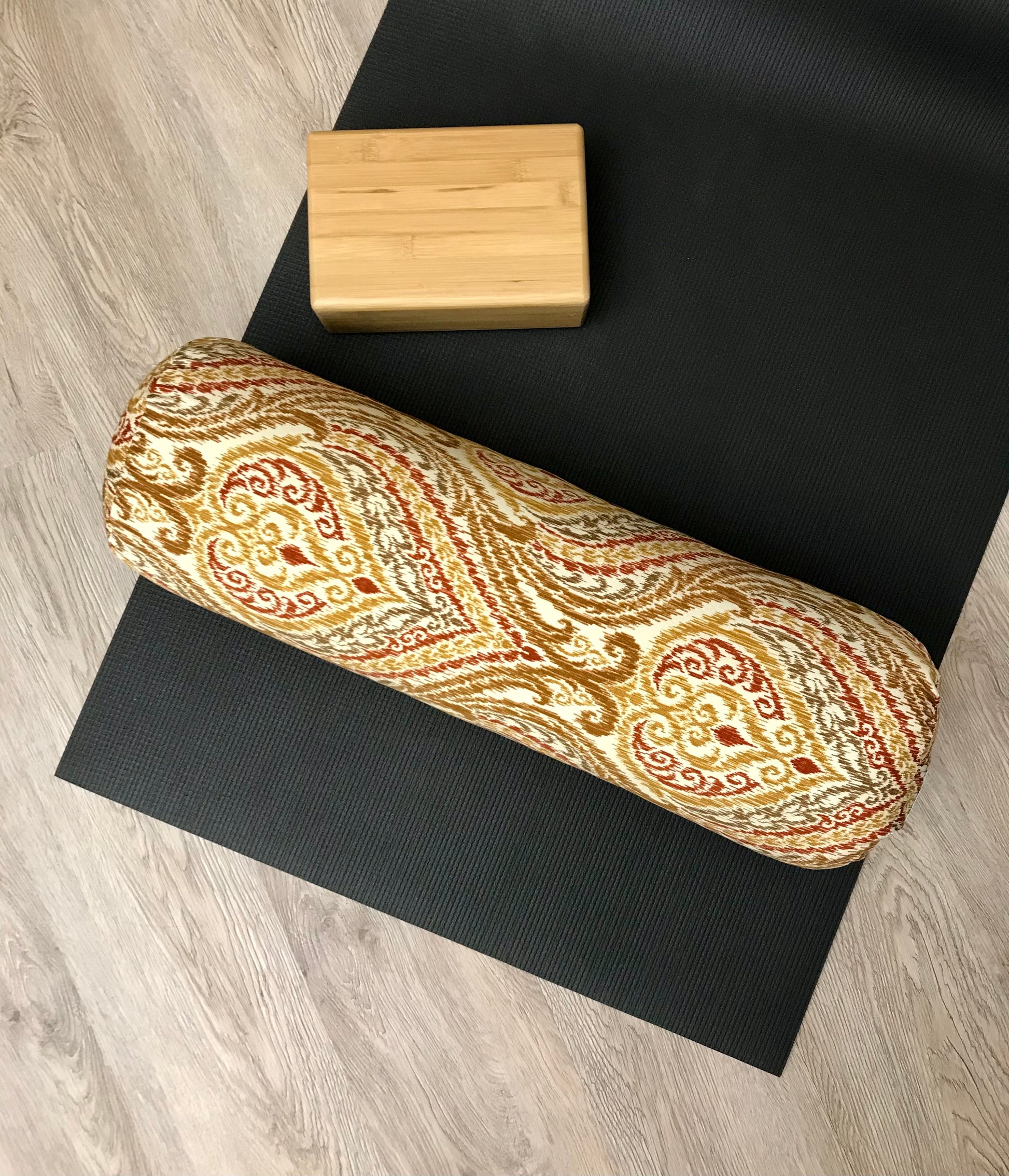 Round yoga bolster in durable cotton canvas, orange and red ikat print fabric. Allergy conscious fill with removeable cover. Made in Canada by My Yoga Room Elements